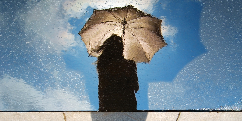 Reflection of person holding umbrella