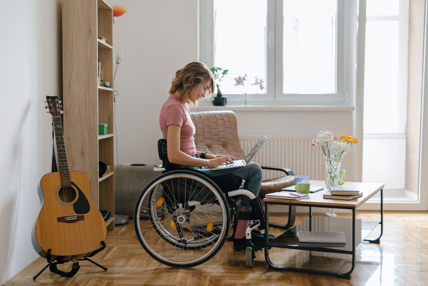 Young Woman In A Wheelchair Working From Home On Her Laptop