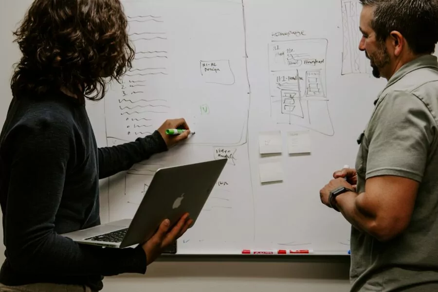 Two people making a plan on a whiteboard