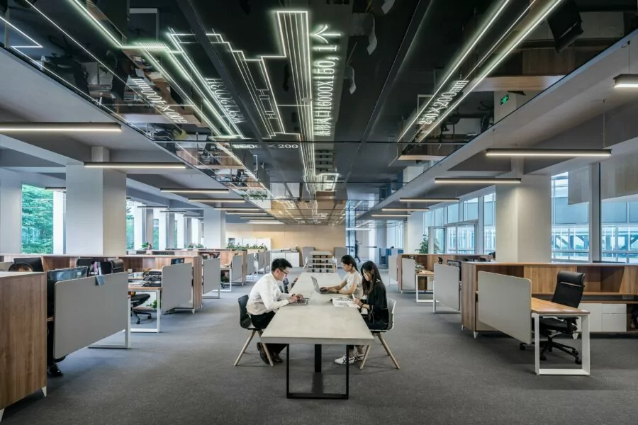 Image of three employees working at a shared desk in an office space