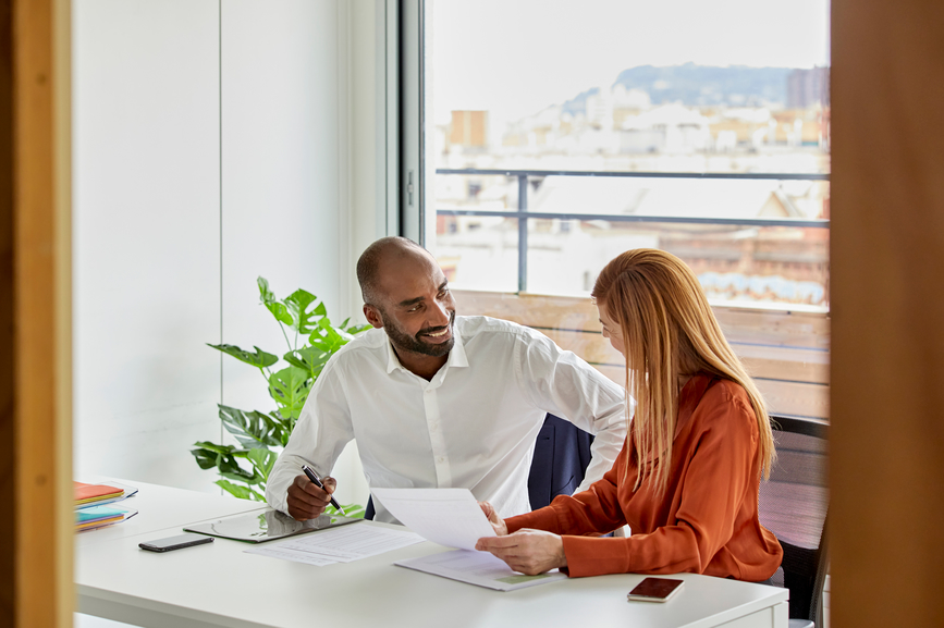 Middle-aged financial advisor with a female customer signing a contract in his office