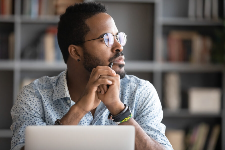 man looking out window with laptop in front of him