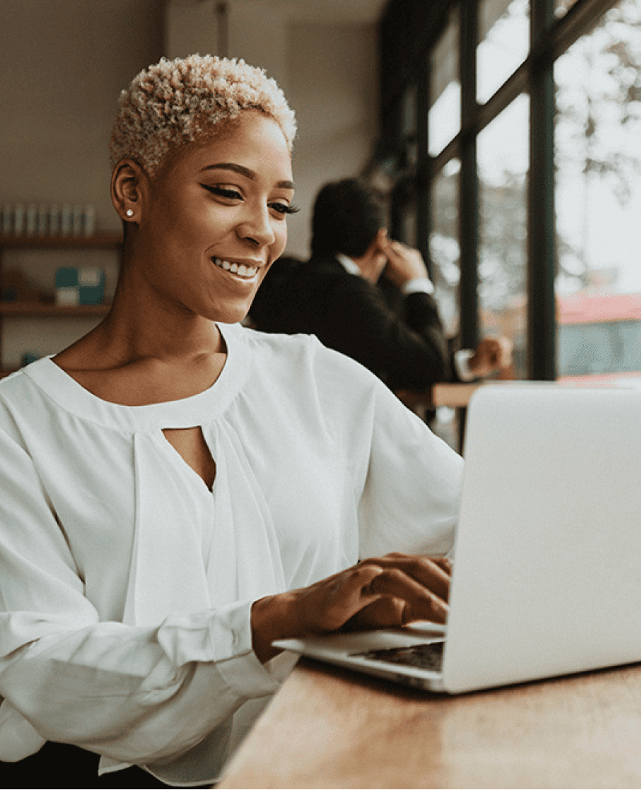 Woman in a coffee shop smiling and using her laptop