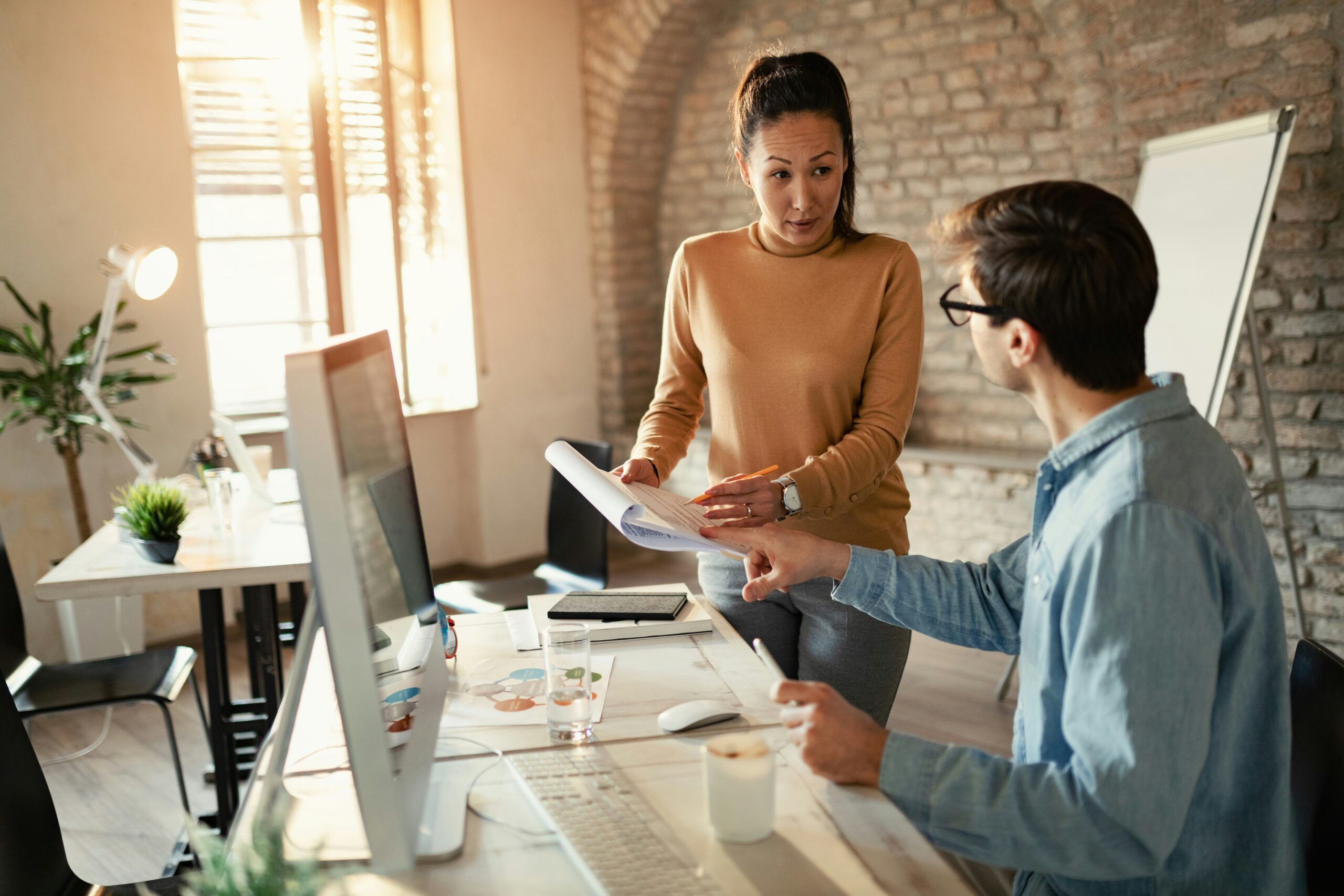 Two coworkers look at a computer together