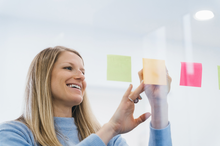 Woman writing tagline ideas on sticky notes